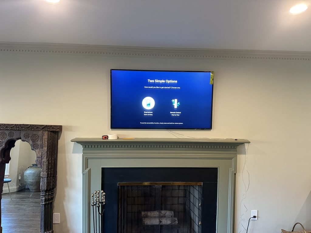 65 inch Samsung Frame TV mounted flush to the wall above a fireplace with a flat bracket in Rockville Centre, NY