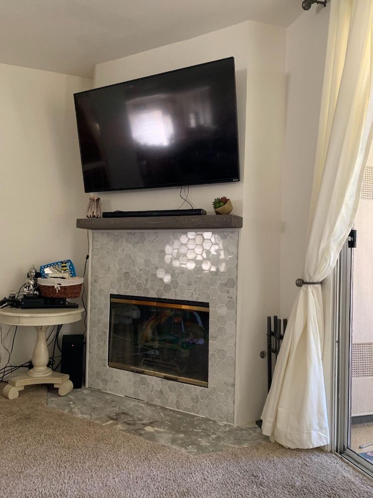 65 inch Samsung OLED TV mounted on a full motion bracket above a fireplace with a connected soundbar in Syosset, NY