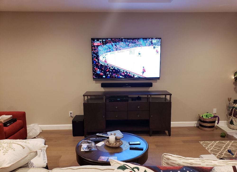 65 inch Samsung TV mounted on a full motion mount with hidden wiring soundbar and subwoofer in Manhasset, NY