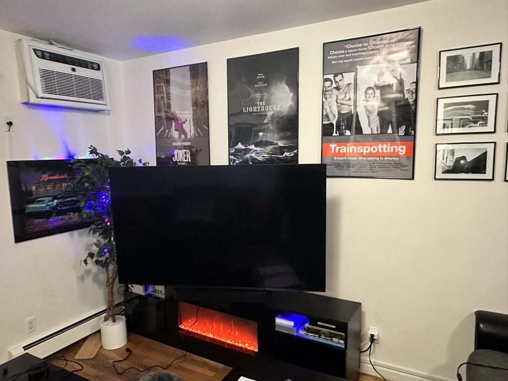 65 inch Sony TV wall mounted above a media console with electric fireplace using a full motion bracket in Massapequa, NY