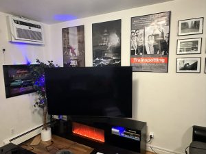 65 inch Sony TV wall mounted above a media console with electric fireplace using a full motion bracket in Massapequa, NY