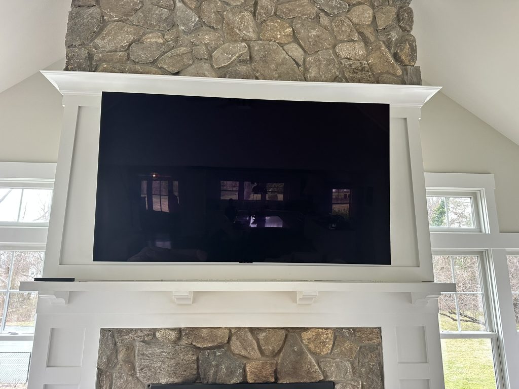 75 inch TV mounted on a full motion bracket within a custom stone fireplace mantel with hidden in wall wiring in Northport, NY