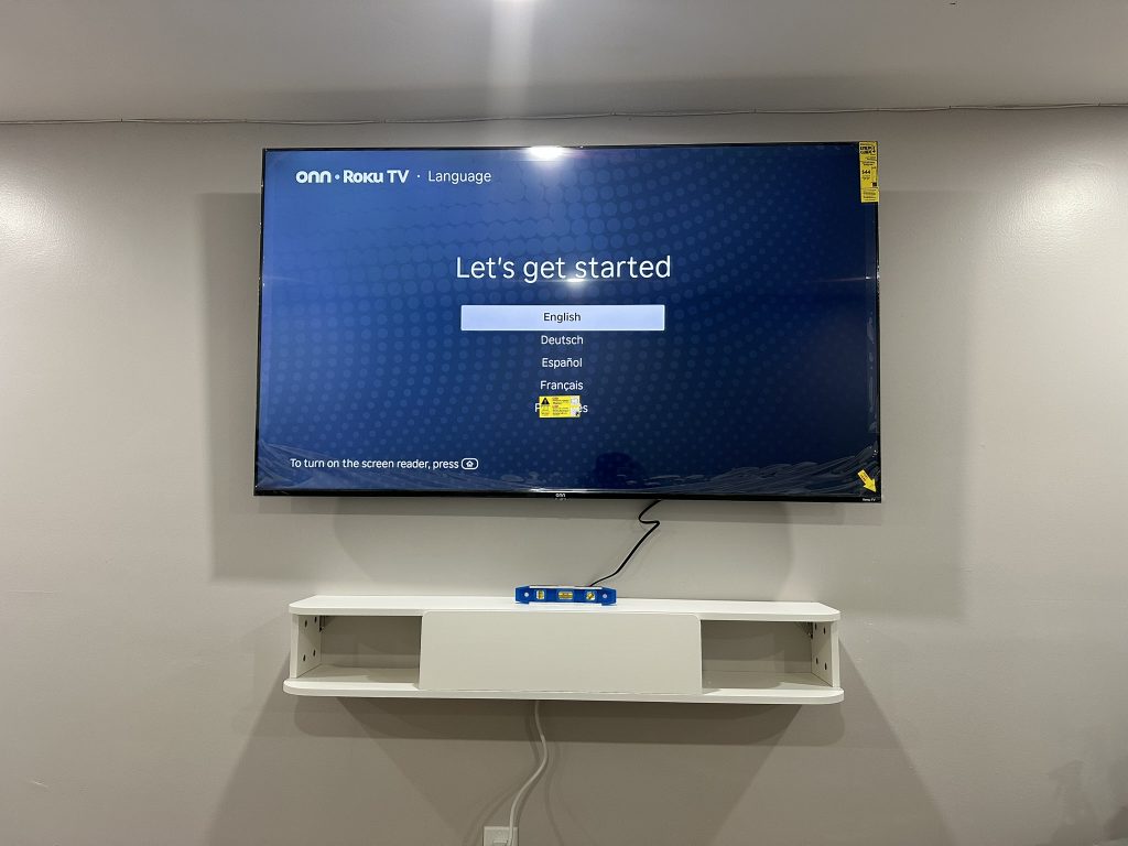 75 inch TV wall mount above white floating shelf in Deer Park, NY