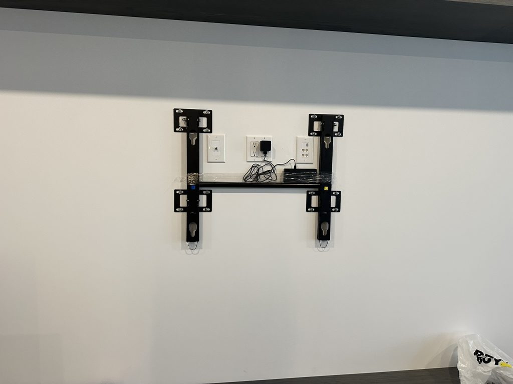Heavy duty flat mount installed for a massive 110 inch Samsung TV with center media shelf and hidden power outlets in Garden City, NY