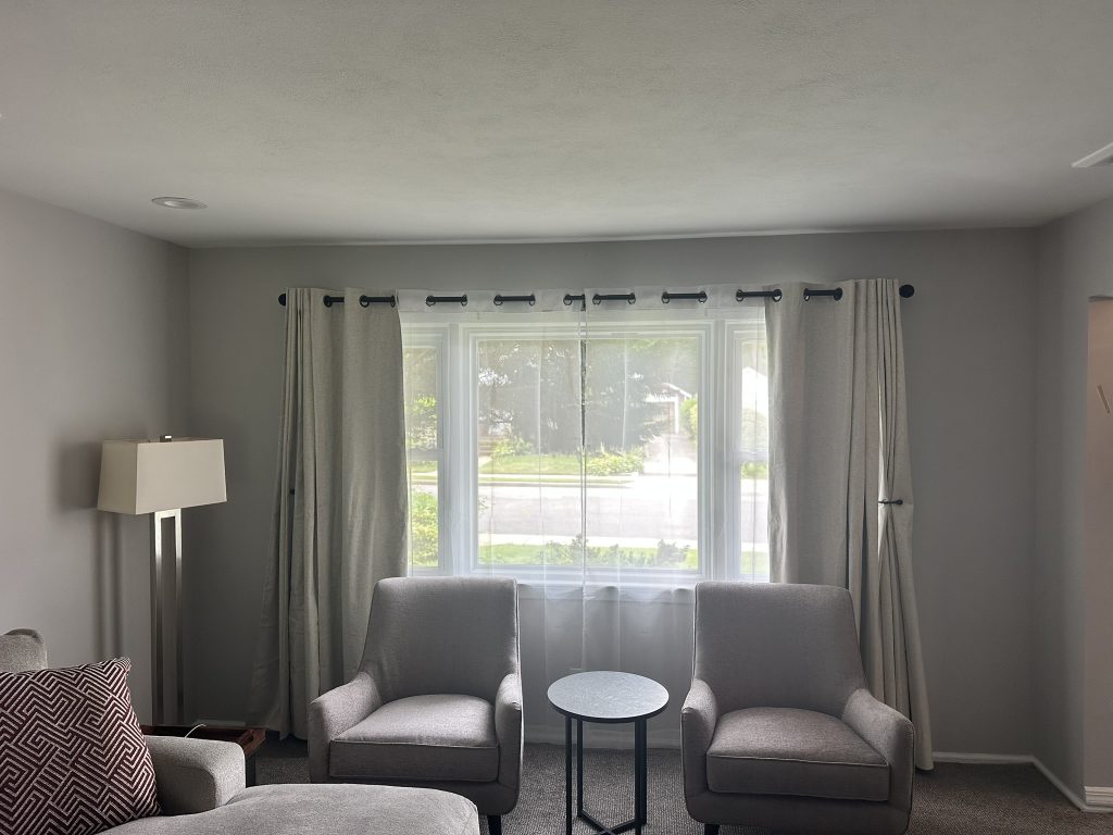 symmetrical grommet curtain setup over a large window in a neutral living room in Northport, NY