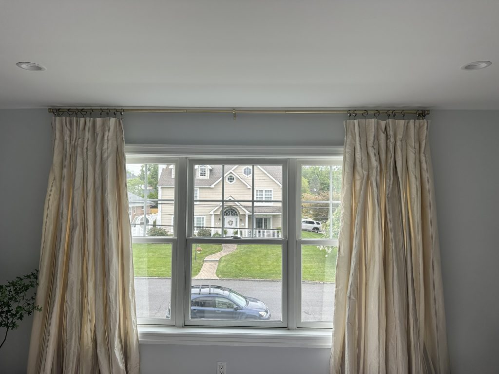 Stylish curtain rod with flowing drapes installed in a bedroom in Manhasset, NY