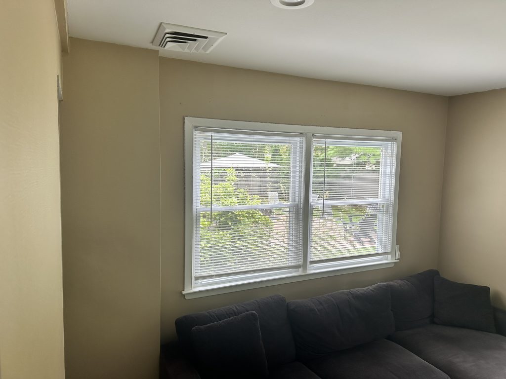 White horizontal window blinds installed on a double window in a living room in Huntington Station, NY